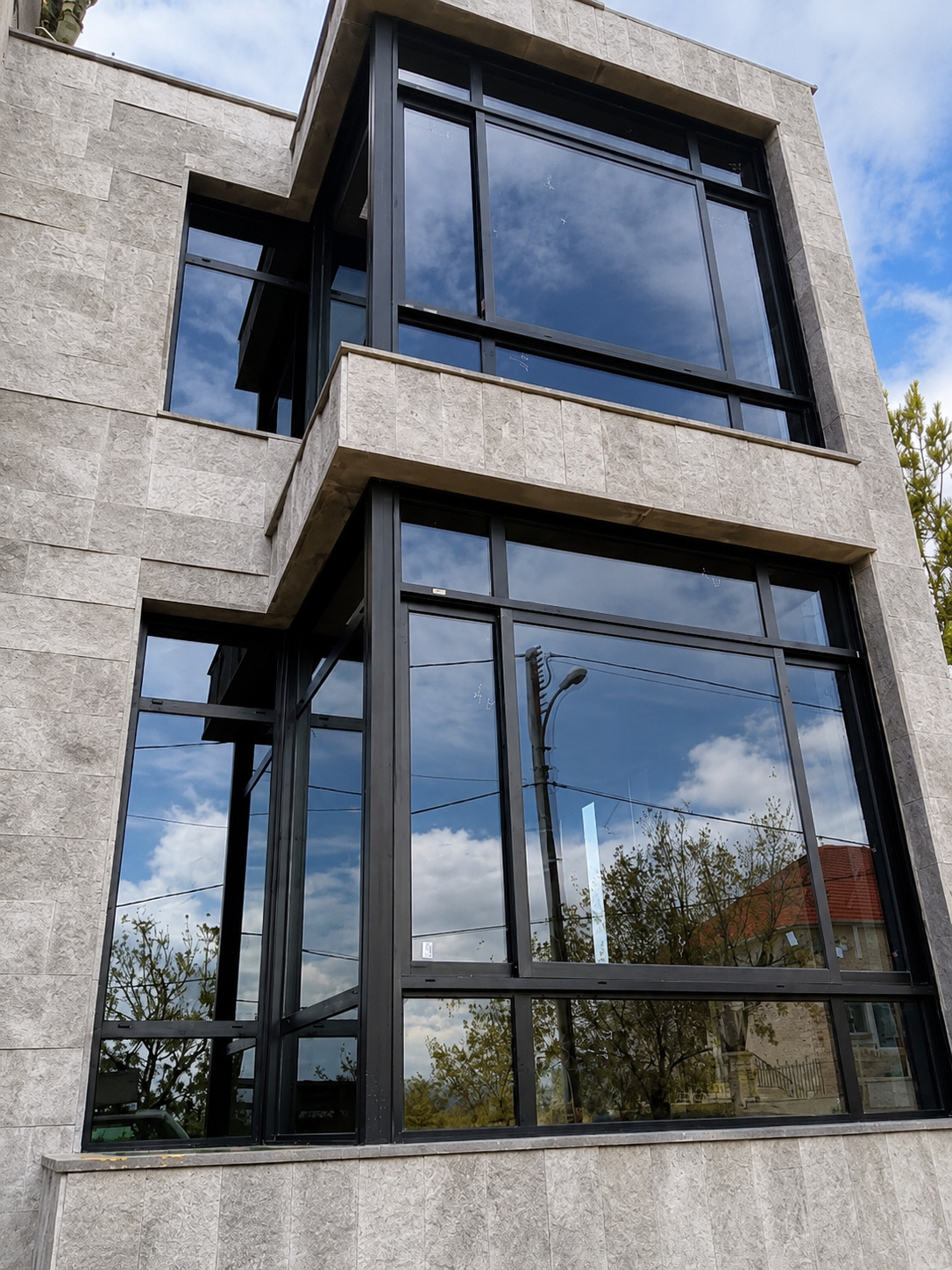 Multi-story glass facade with black aluminum framing, fabricated and installed by Najd Aluminum.